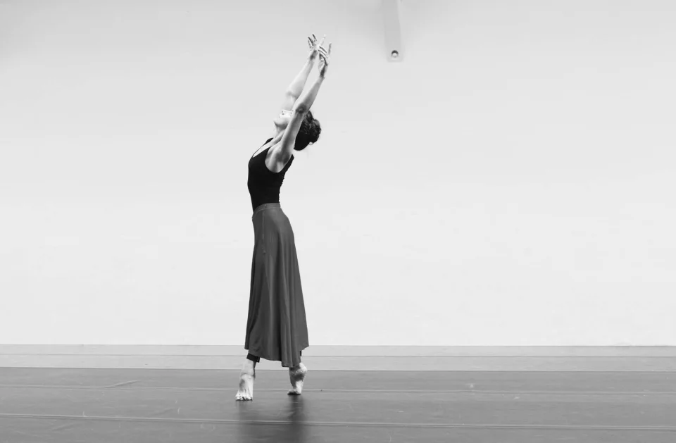 Amy reaching upwards in a bright rehearsal studio